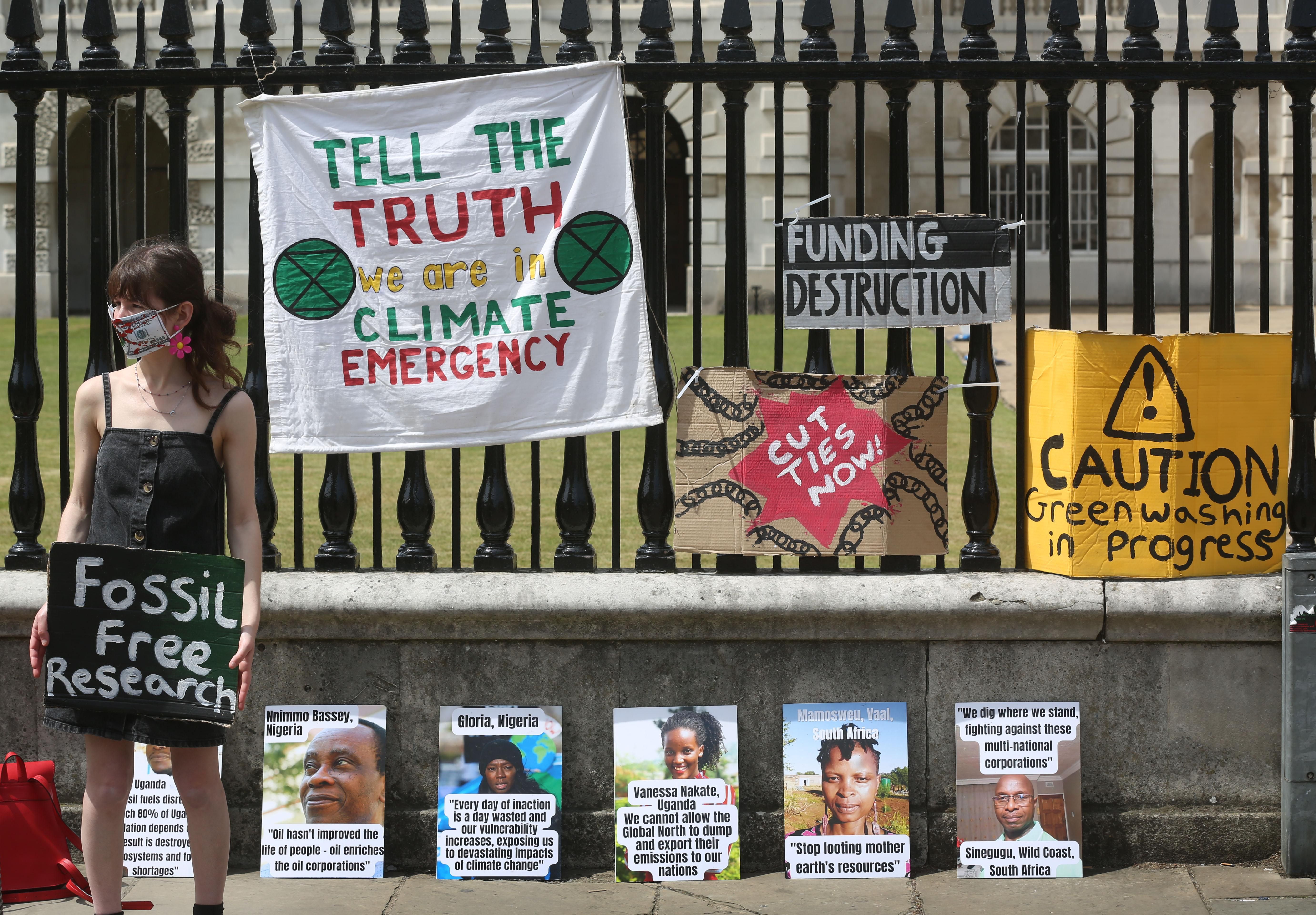 A climate activist holds a sign saying 'Fossil Free Research' outside Cambridge University on June 16, 2022.