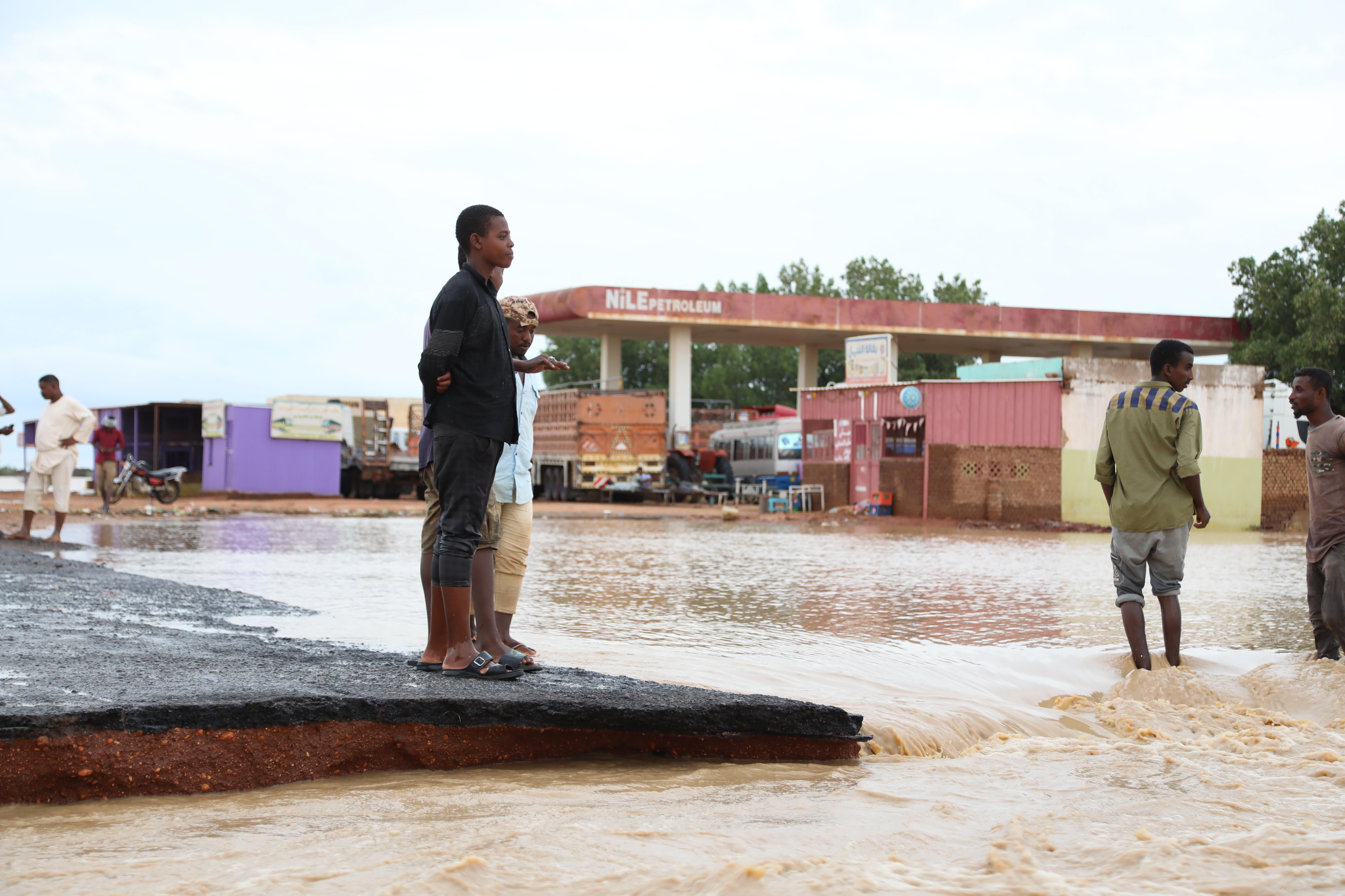 People stand on a damaged road after deadly flooding in Al Jazirah, Sudan on August 20, 2022.