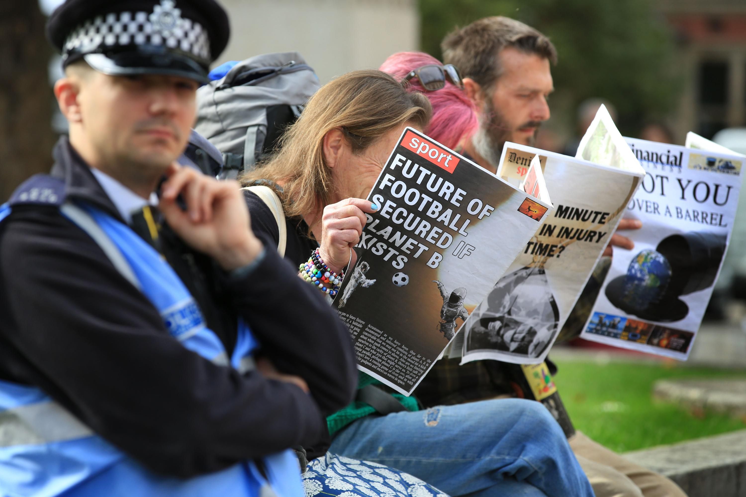 Demonstrators read spoof newspapers