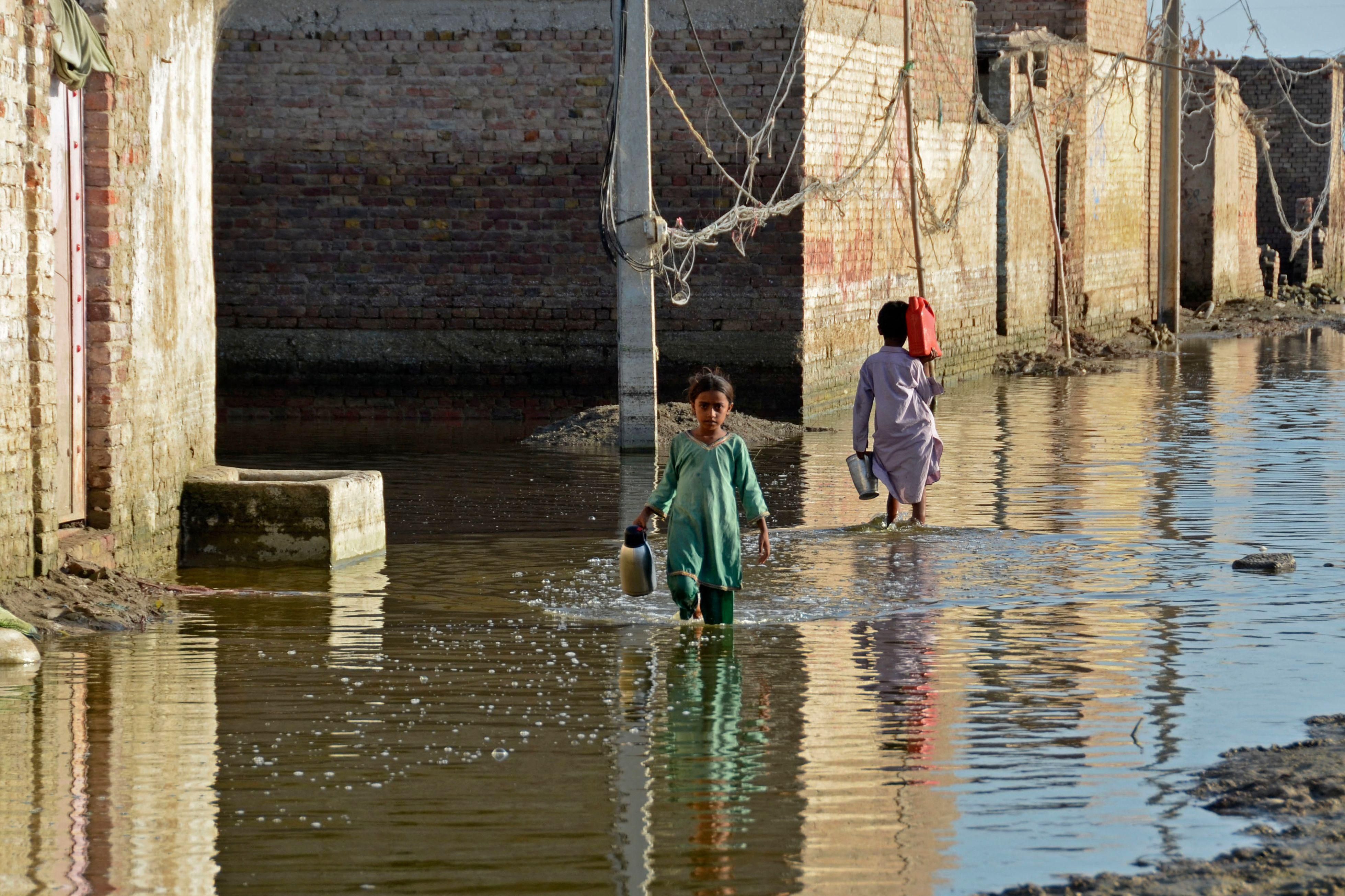 Children wade through a flooded street in the Jaffarabad district of Pakistan's Balochistan province on October 4, 2022.