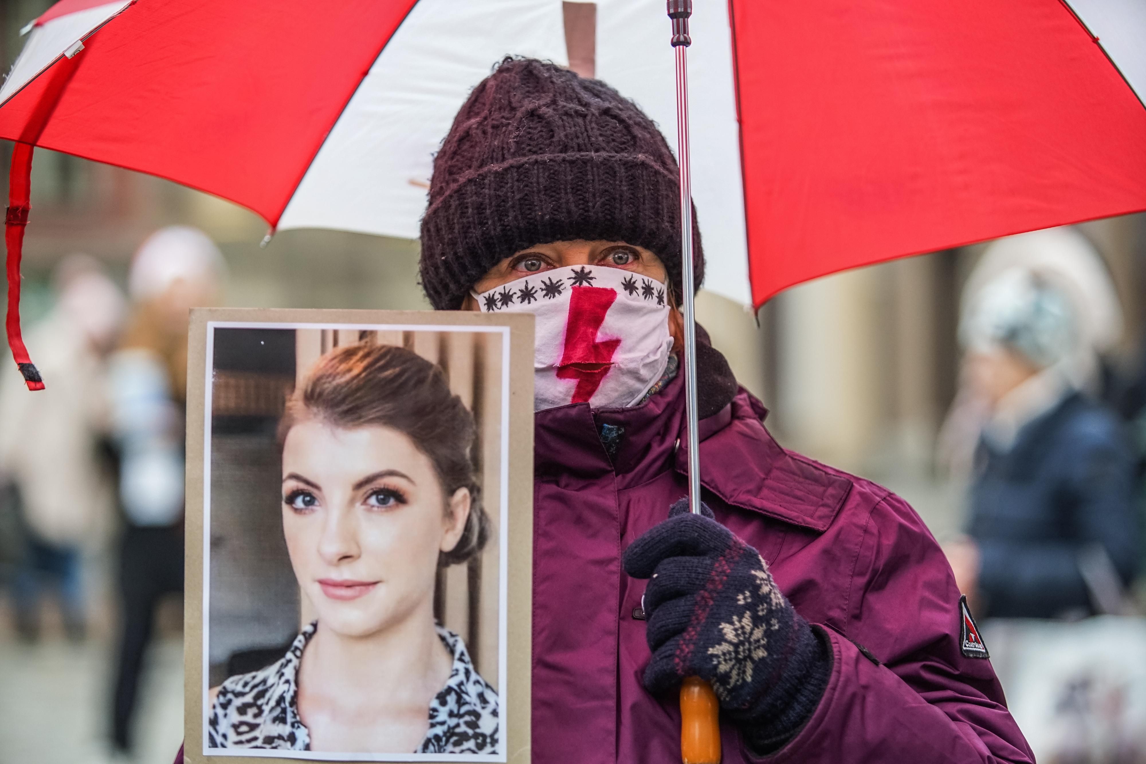 A woman holds a picture of a woman who died due to Poland's abortion ban
