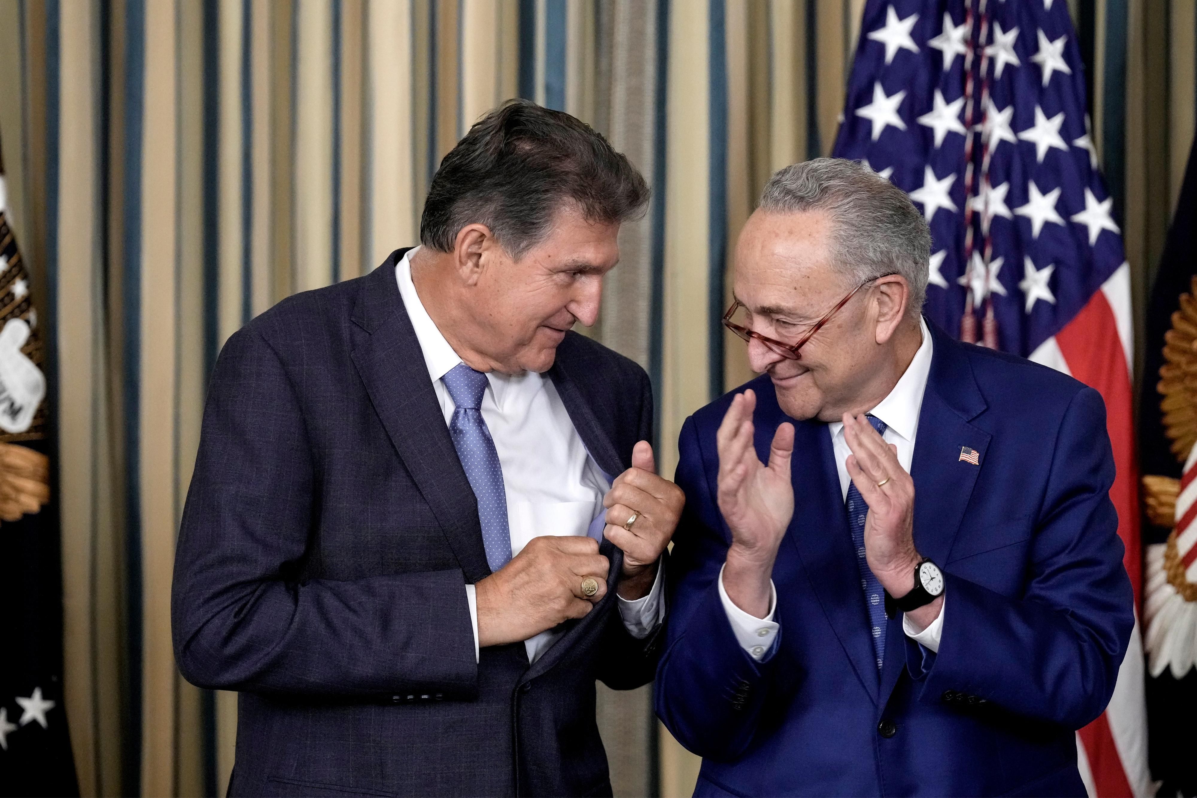 Sen. Joe Manchin and Senate Majority Leader Chuck Schumer clap during a White House event