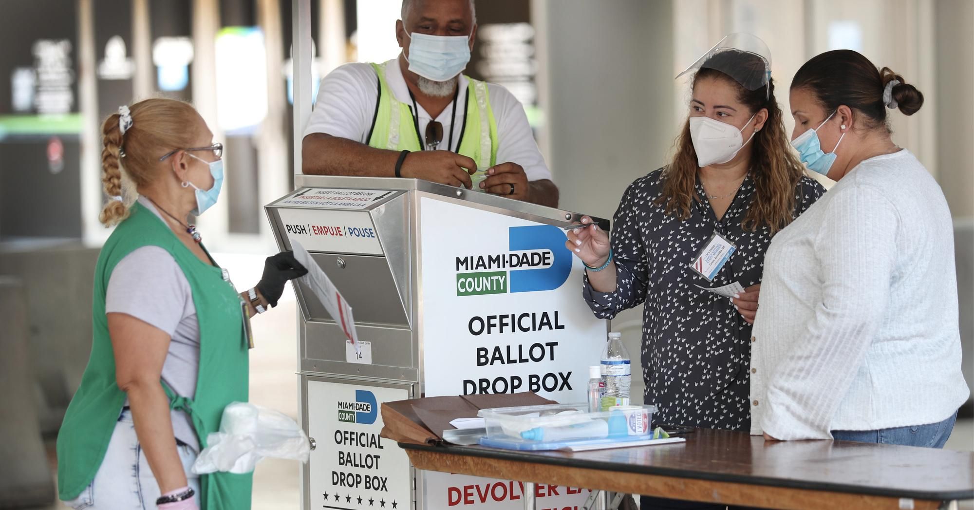Poll workers help a voter put their mail-in ballot in an official Miami-Dade County ballot drop box on August 11, 2020 in Florida. (Photo: Joe Raedle/Getty Images)