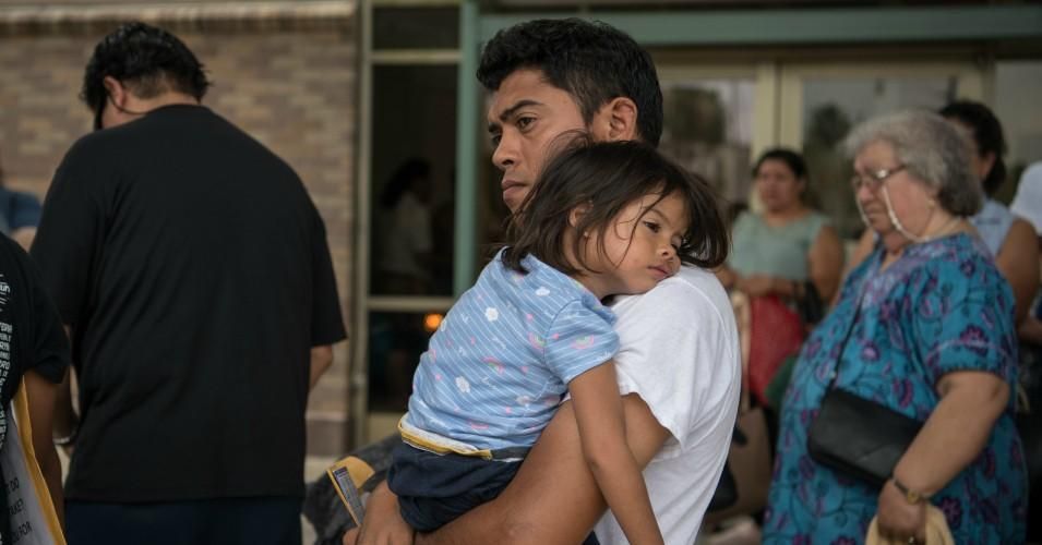 A Honduran migrant recently released from federal detention boards a bus while carrying his two-year-old daughter at a bus depot on June 11, 2019, in McAllen, Texas.