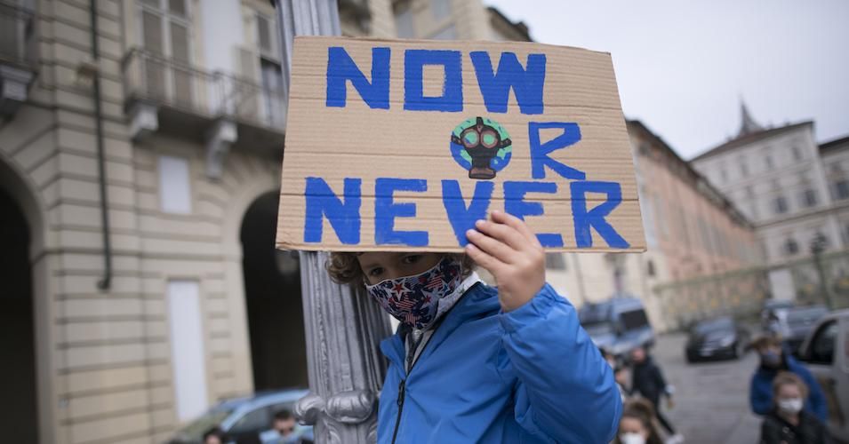 A child wears a protective mask and holds a sign during a protest as part of the Fridays for Future movement to call for action against climate change on October 9, 2020 in Turin, Italy. 