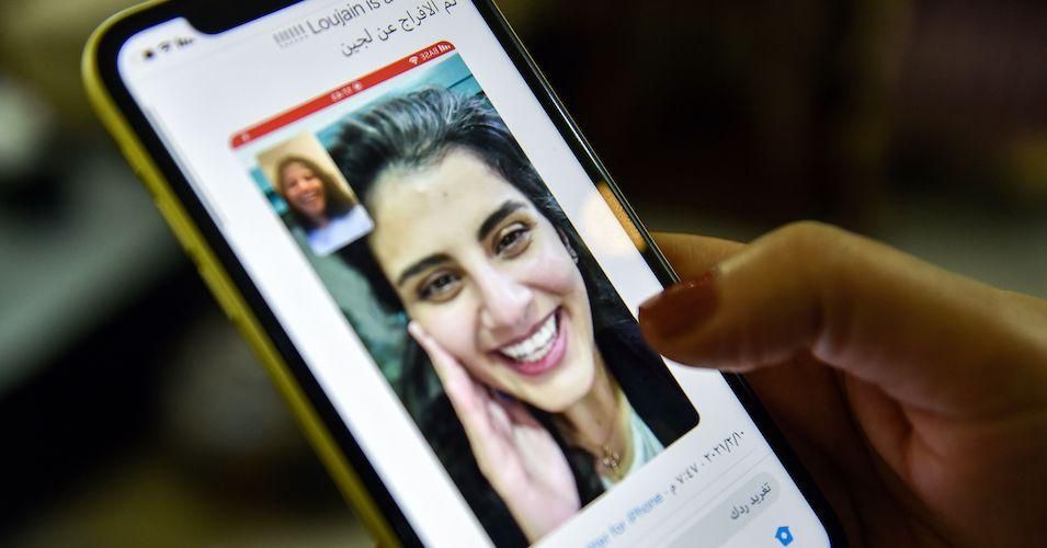 This picture taken February 10, 2021 in Saudi Arabia's capital Riyadh shows a woman viewing a tweet posted by the sister of Saudi activist Loujain al-Hathloul, Lina, showing a screenshot of them having a video call following Hathloul's release after nearly three years in detention. 