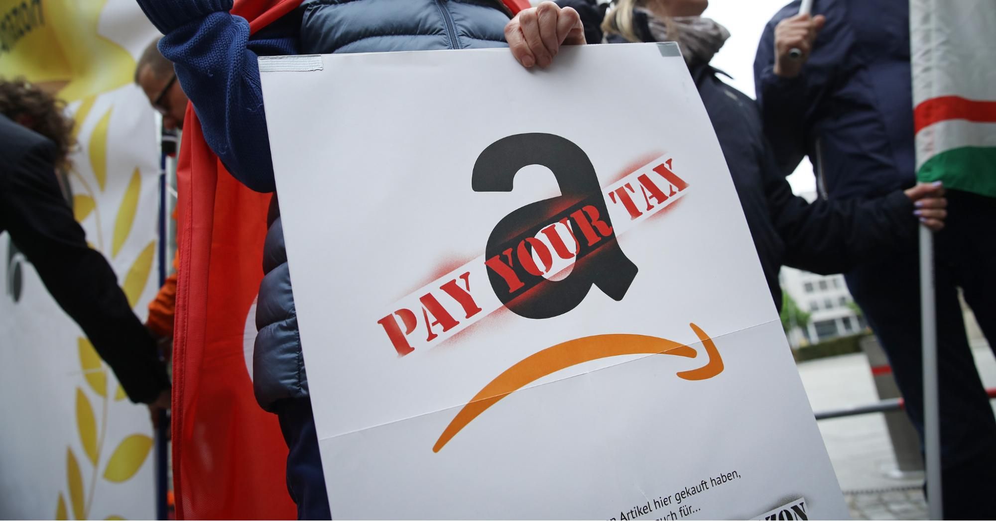 An activist holding a sign demanding online retailer Amazon pay its share of taxes joins a protest outside the Axel Springer building on April 24, 2018 in Berlin, Germany. (Photo: Sean Gallup via Getty Images)