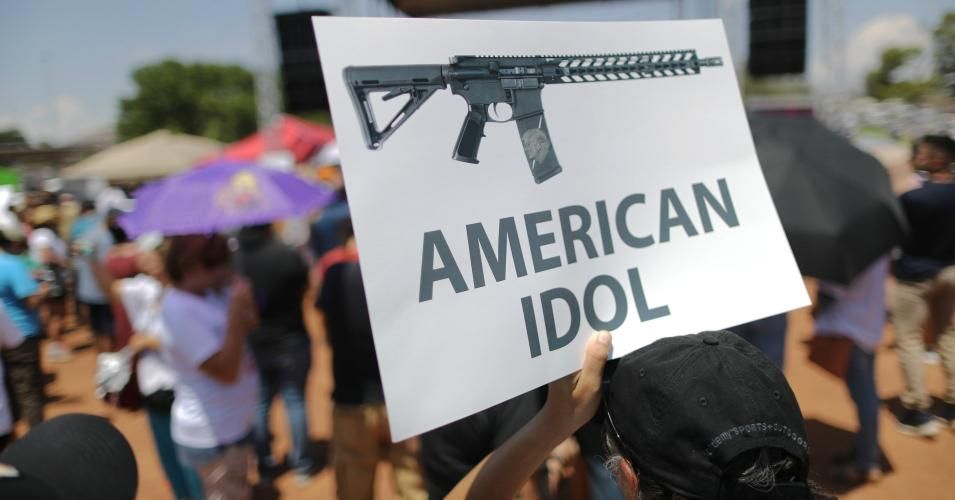 A demonstrator holds a sign depicting an assault rifle at a protest against President Trump's visit, following a mass shooting which left at least 22 people dead, on August 7, 2019 in El Paso, Texas. Protestors also called for gun control and denounced white supremacy. Trump is scheduled to visit the city today. A 21-year-old white male suspect remains in custody in El Paso which sits along the U.S.-Mexico border. (Photo: Mario Tama/Getty Images)