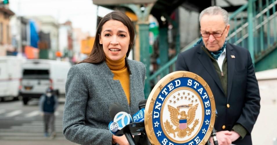 Democratic Congresswoman from New York Alexandria Ocasio-Cortez speaks as now Senate Majority Leader Chuck Schumer listens during a press conference in the Corona neighborhood of Queens on April 14, 2020 in New York City