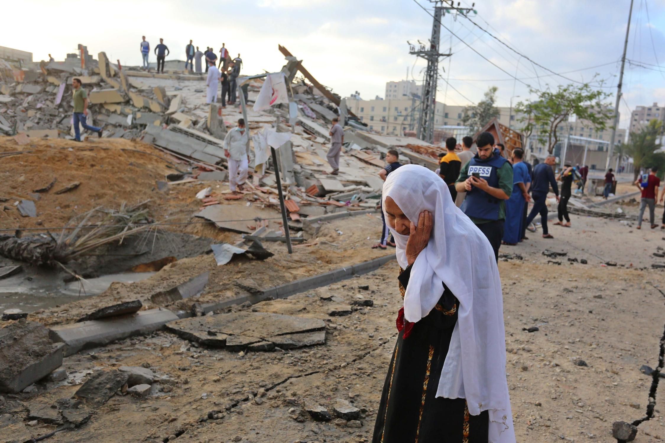 Palestinians stand near ruins of buildings destroyed by ongoing Israeli airsrtikes in Beit Lahia, Gaza on May 13, 2021.