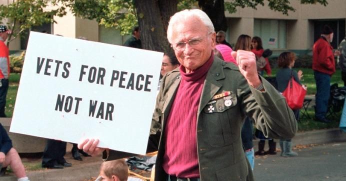 A vet for peace walks during a parade