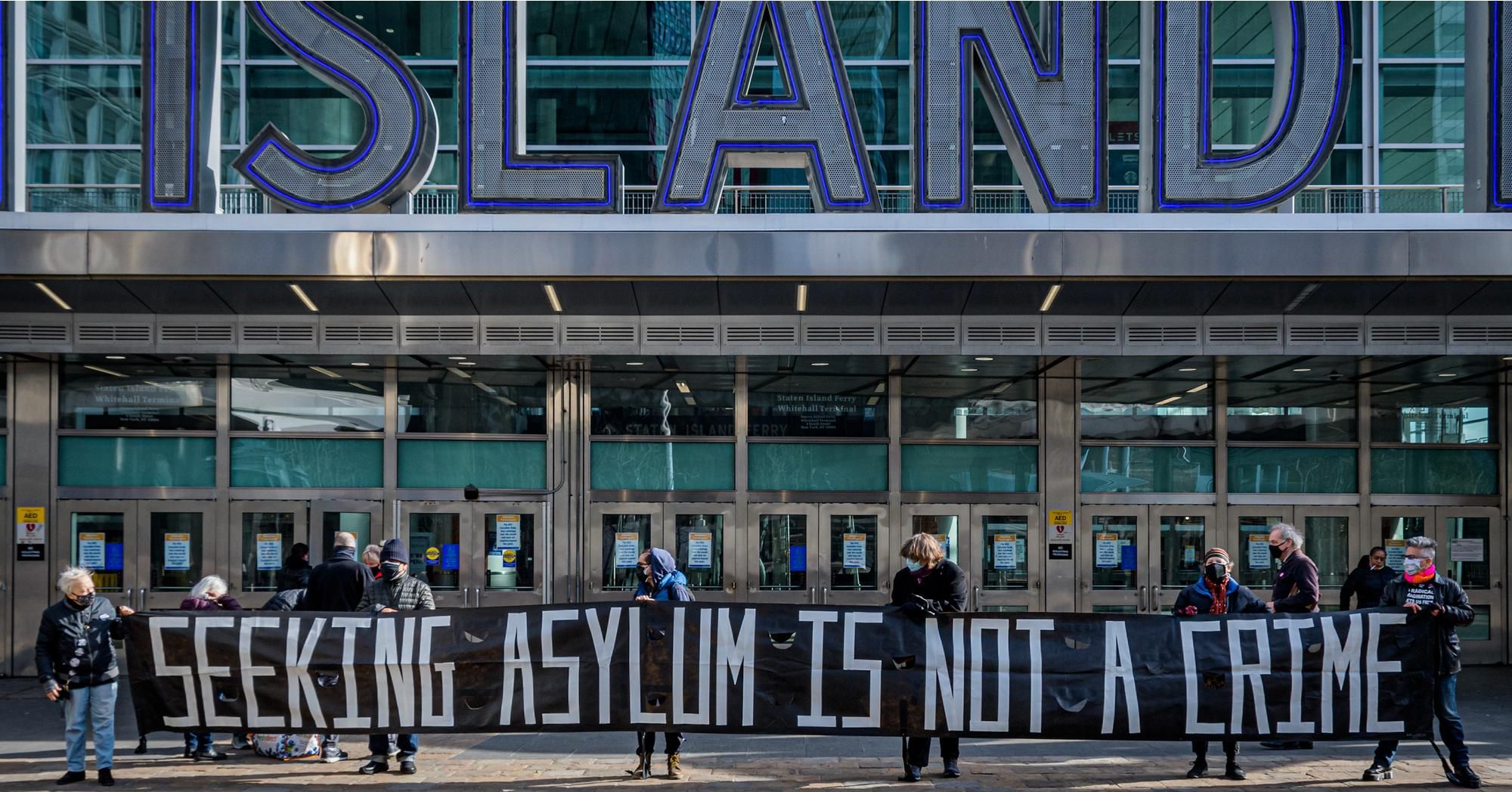 Protesters hold a banner reading "Seeking Asylum Is Not a Crime" at an April 22, 2021 demonstration at the Staten Island Ferry in New York City. (Photo: Erik McGregor/LightRocket via Getty Images)