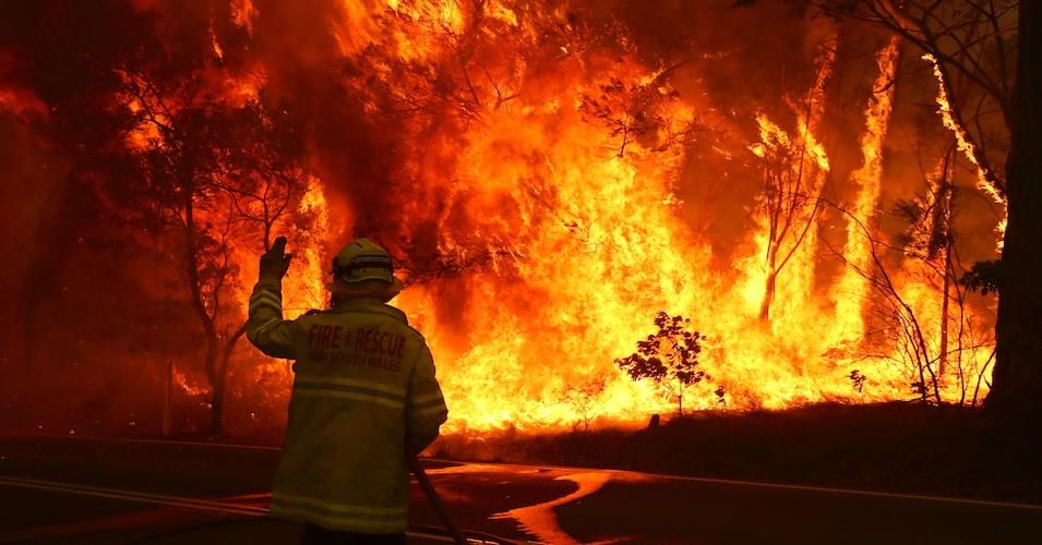 Fire and Rescue personnel run to move their truck as a bushfire burns next to a major road and homes on the outskirts of the town of Bilpin on December 19, 2019 in Sydney, Australia.