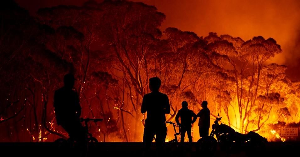 Residents look on as flames burn through bush on Jan. 4, 2020 in Lake Tabourie, Australia.