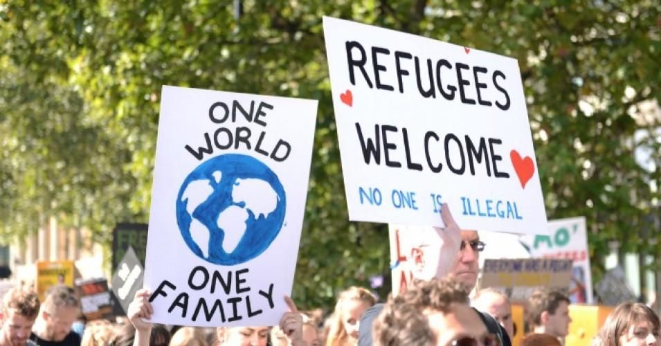 Signs read: "Refugees Welcome" and "One World One Family"