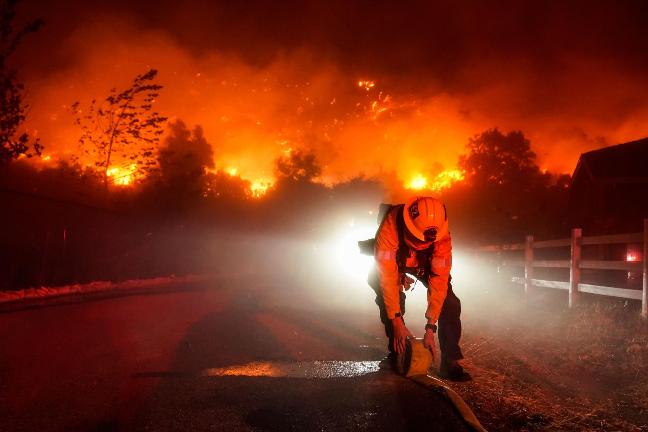 Firefighters battle the Bond Fire, started by a structure fire that extended into nearby vegetation, along Silverado Canyon Road on Thursday, December 3, 2020 in Silverado, California.