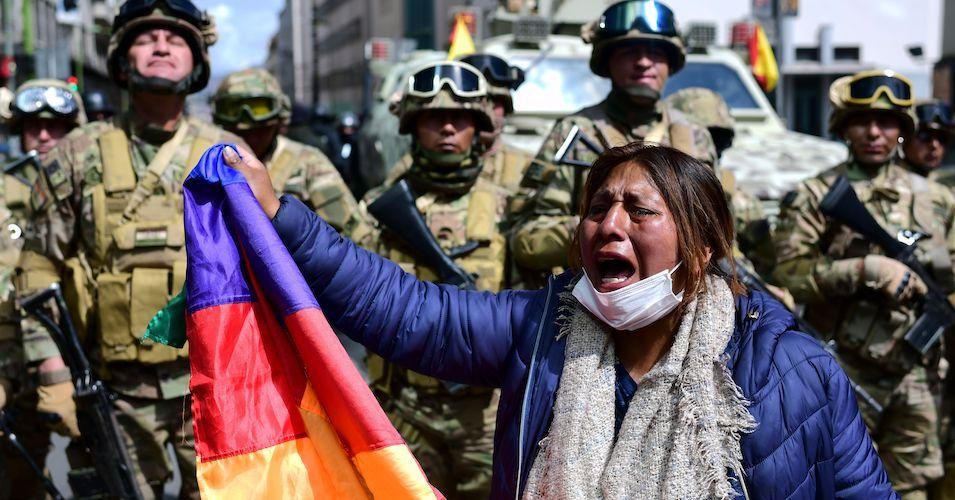 A Bolivian indigenous woman, supporter of Bolivian ousted president Evo Morales, holds a Wiphala flag—representing native peoples—during a protest against the interim government in La Paz on November 15, 2019.