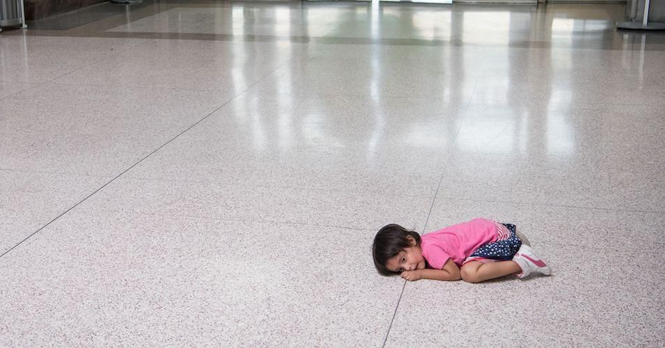 A young migrant girl sits on the floor as her father, recently released from federal detention with other Central American asylum seekers, gets a bus ticket at a bus depot on June 11, 2019, in McAllen, Texas.