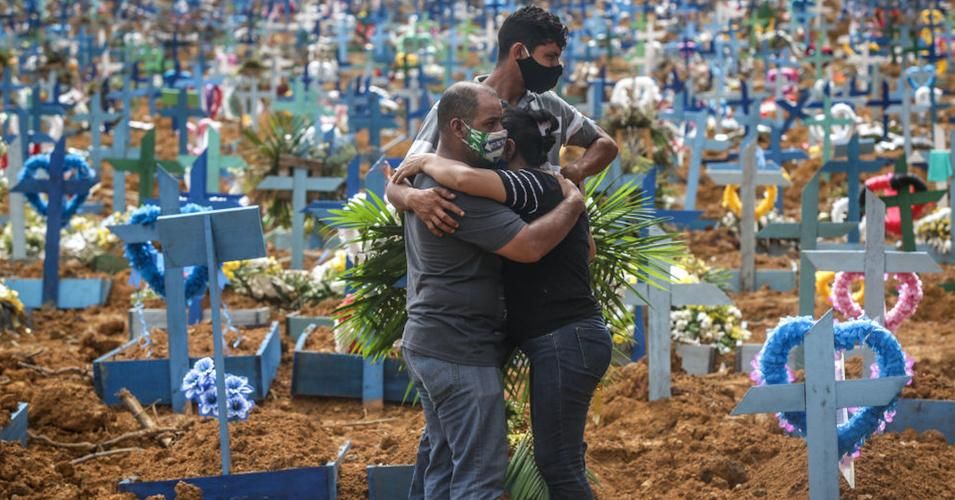 Relatives of a Brazilian Covid-19 victim embrace in a cemetery built for the mass burial of people killed by the pandemic in Manaus, Amazonas. (Photo: Andre Coelho/Getty Images) 