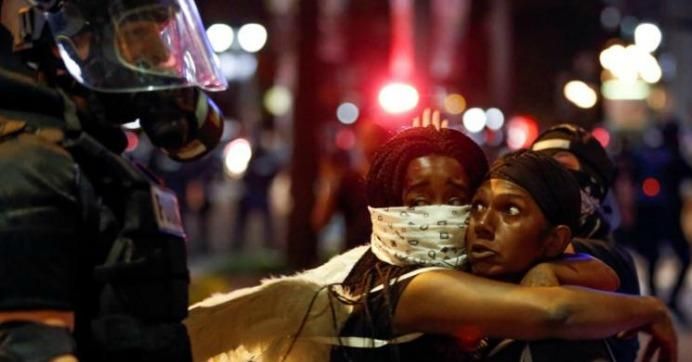  Two women embrace while looking at a police officer in riot gear during a protest against the police shooting of Keith Lamont Scott in uptown Charlotte, North Carolina on September 21, 2016. (Photo: Jason Miczek/ Reuters)