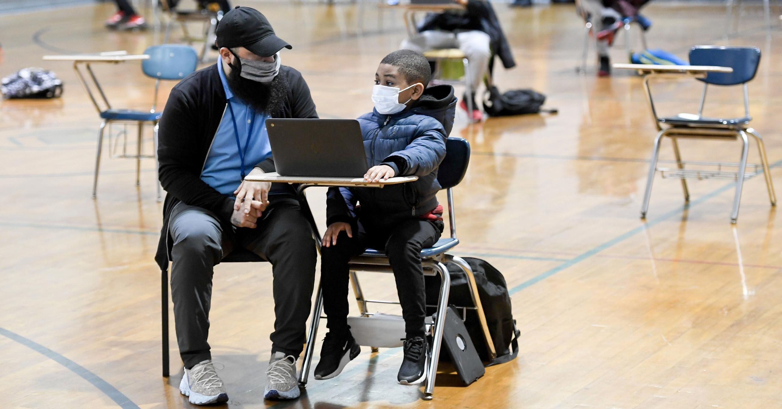 Jordan Rodriguez, director of the Mulberry Street club, works with Santana Sanford, 7, a second grade student, as he does his school work on a laptop computer in Reading, Pennsylvania on January 19, 2021. (Photo: Ben Hasty/MediaNews Group/<em>Reading Eagle</em> via Getty Images)