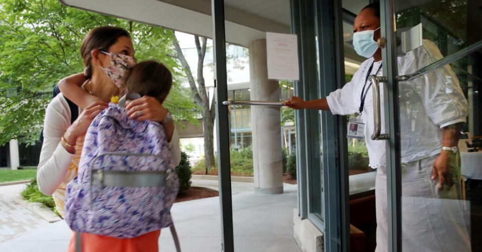 Frances Taplett says goodbye to her daughter, Claire, 5, while dropping her off with Debra Davis, the director of the Whitehead Institute at Bright Horizons in Cambridge, Massachusetts on August 13, 2020. (Photo: Craig F. Walker/The Boston Globe via Getty Images)
