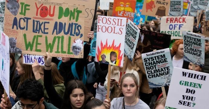 Protesters hold signs at the YouthStrike4Climate student march on April 12, 2019 in London.