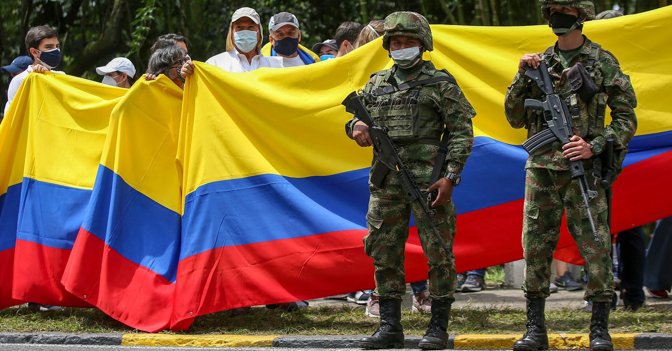 Colombian soldiers stand by as people march during a national strike in the city of Cali on May 8, 2021.