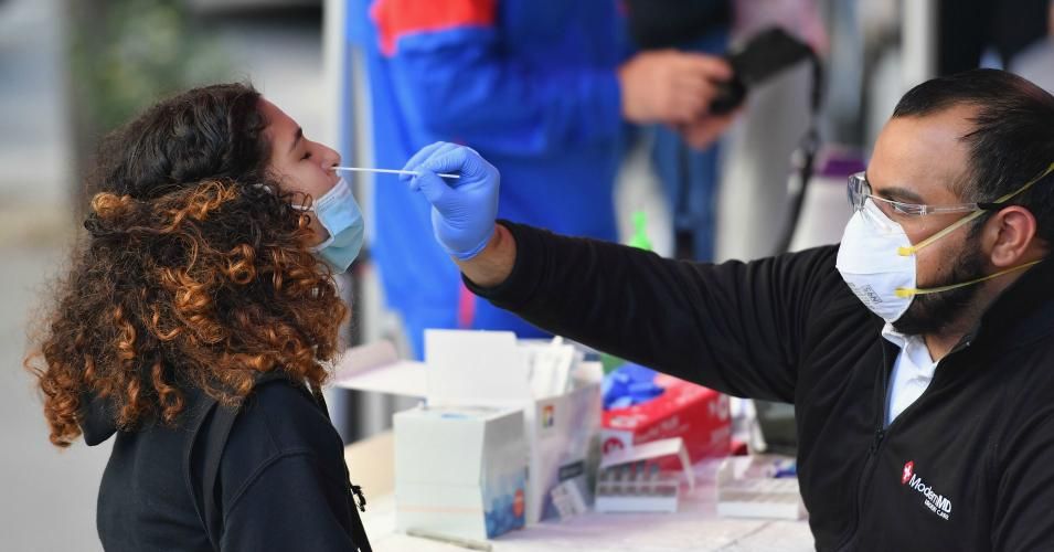 A medical worker takes a nasal swab sample from a student to test for COVID-19 at the Brooklyn Health Medical Alliance urgent care pop up testing site as infection rates spike.