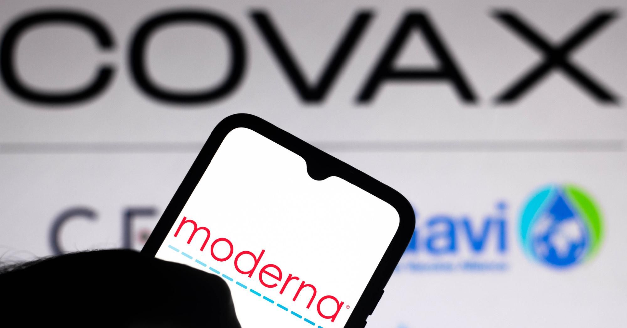 In this photo illustration, the Moderna logo is seen displayed on a smartphone screen with the logo of Covax in the background.