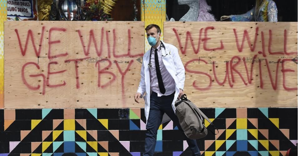 A doctor with the Haight Ashbury Free Clinic, walks by a supportive sign on a boarded-up shop while speaking with homeless people about the coronavirus (COVID-19) in the Haight Ashbury area of San Francisco California on March 17, 2020. (Photo: Josh Edelson / AFP via Getty Images)