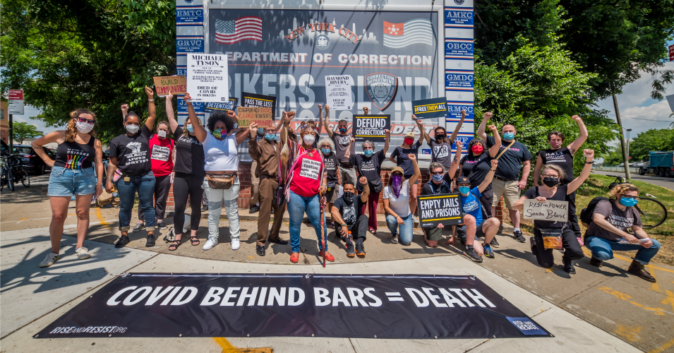 Participants behind a banner reading "COVID BEHIND BARS = DEATH" attend a rally at Rikers Island in New York. 