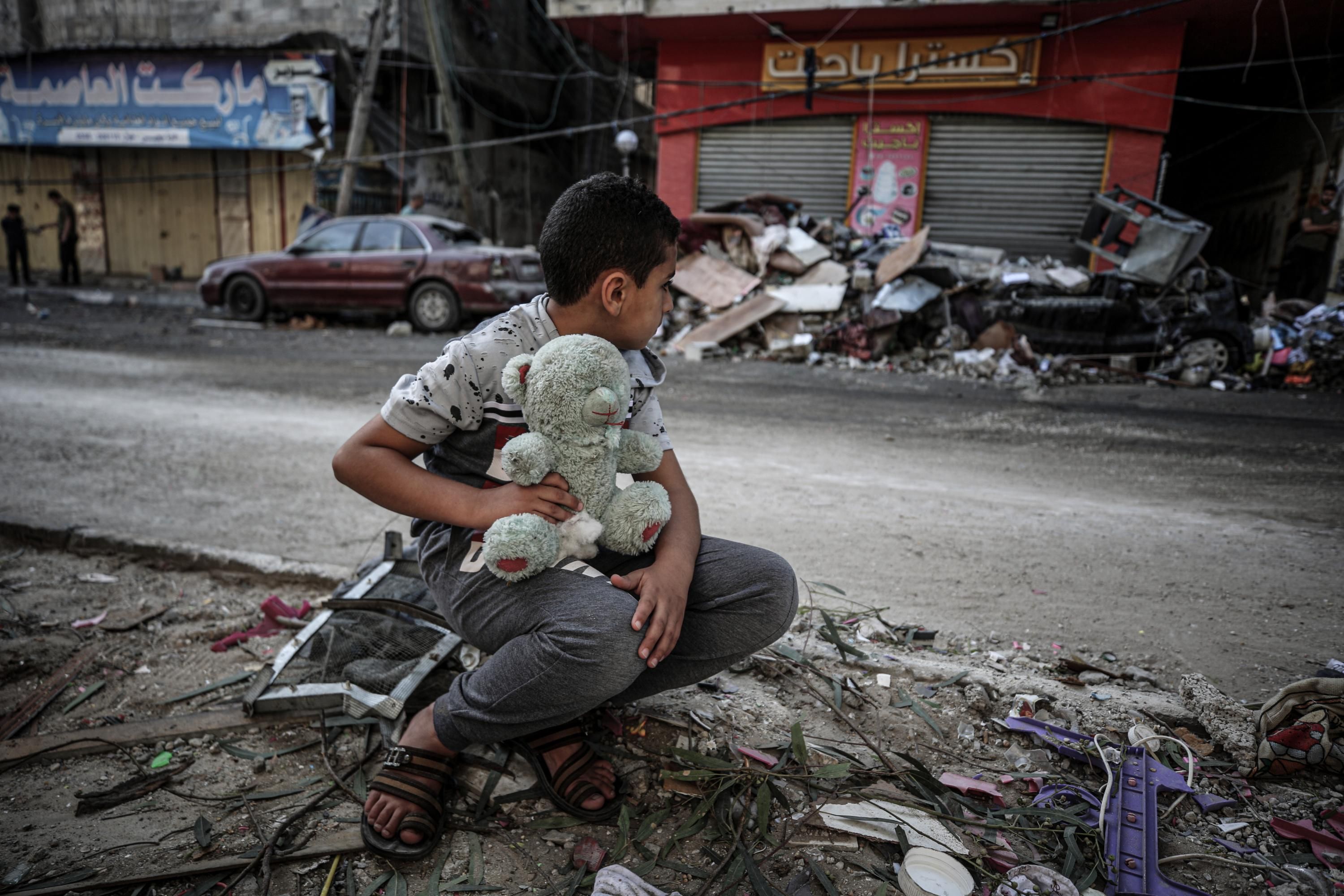 A boy with his teddy bear sits on the ruins of buildings destroyed by Israeli airstrikes in the Sheikh Ridvan neighborhood in Gaza City on May 19, 2021. (Photo: Ali Jadallah/Anadolu Agency via Getty Images)