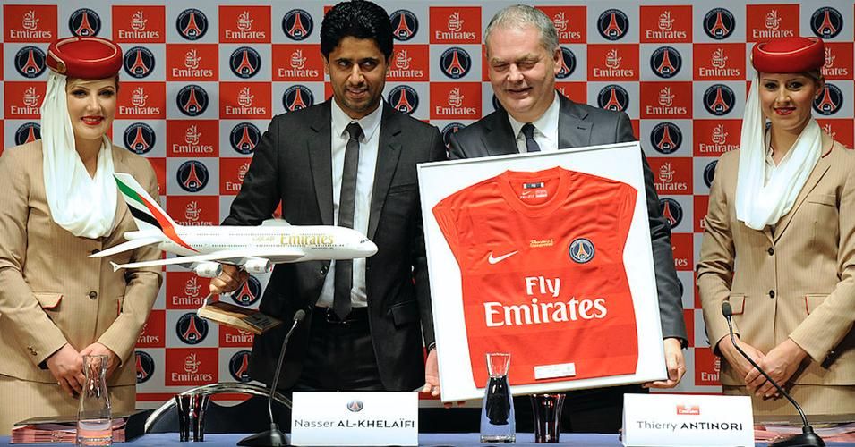 Paris Saint-Germain (PSG) football club's chairman Nasser Al-Khelaifi (L) and the Executive Vice President of Emirates company Thierry Antinori present a PSG jersey, reading "Parisians and Champions", during a press conference on May 17, 2012 at the Parc des Princes stadium in Paris. (Photo: BERTRAND GUAY/AFP via Getty Images)