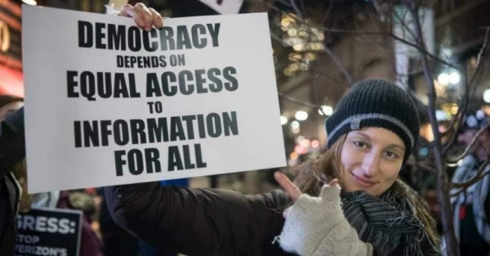 placard reads: Democracy depends on equal access to information to all