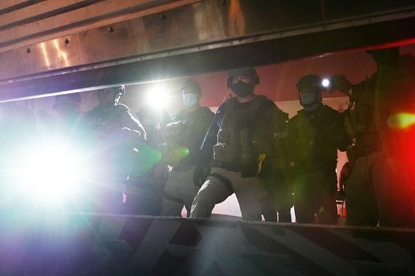 Federal officers shine flashlights from inside a closing garage door at the rear entrance to the Mark O. Hatfield U.S. Courthouse on July 31, 2020 in Portland, Oregon. (Photo: Nathan Howard/Getty Images)