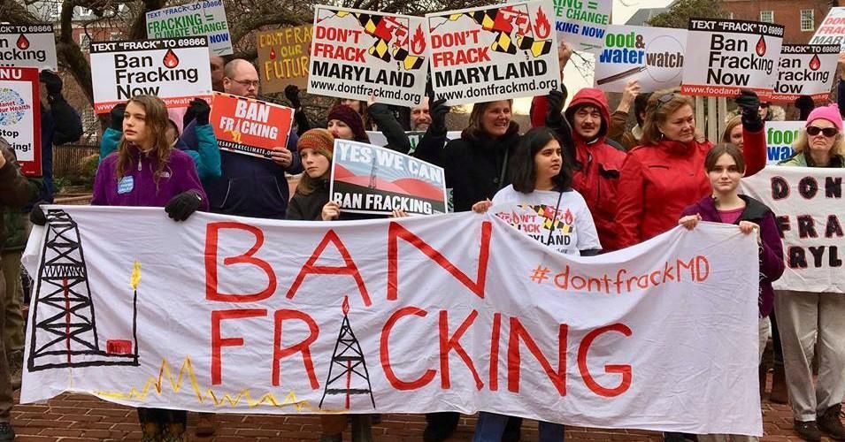 Anti-fracking demonstrators hold a banner and signs