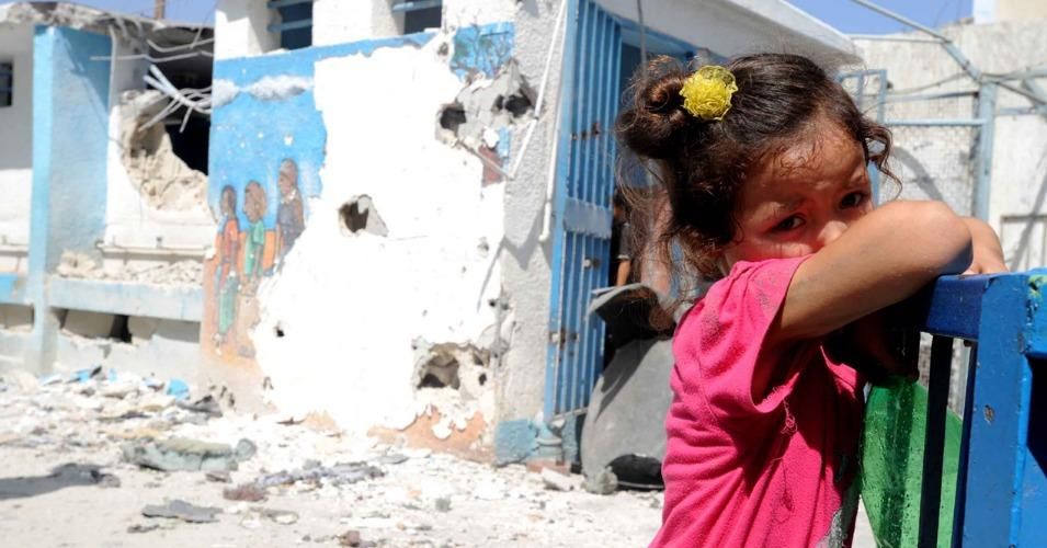 A child stands in the aftermath of a shelling in Jabalia, Gaza. An estimated 500 children were killed in the 2014 attack. (Photo: Shareef Sarhan/UNRWA Archives). 