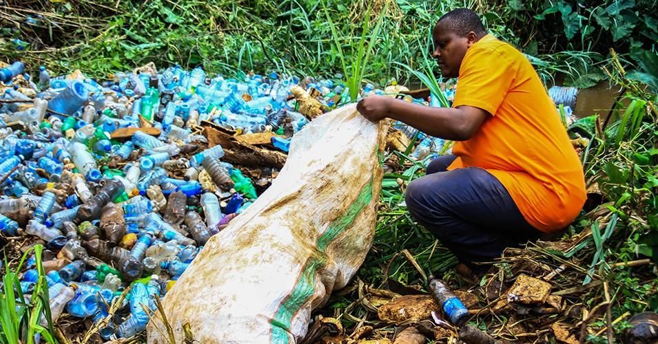 A volunteer removes plastic bottles and other trash polluting Ruaka River in Nairobi, Kenya. An increasing production of single-use plastics for beverage and other uses has become a nightmare in solid waste management in the country. (Photo: James Wakibia/SOPA Images/LightRocket via Getty Images)