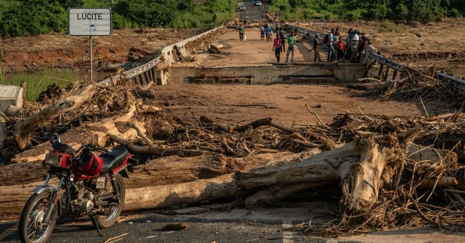 People stand on top of a broken bridge, damaged during Cyclone Idai