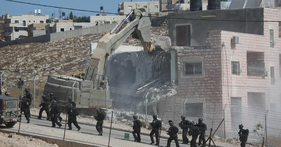 Israeli forces demolish a building with bulldozers 