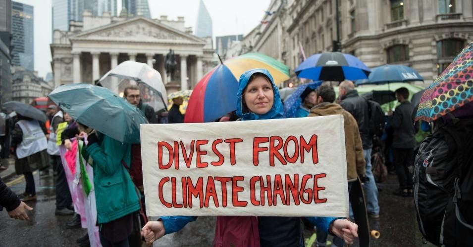 An Extinction Rebellion protester holds up a placard saying "Divest from climate change" as they block the roads outside the Bank of England on October 14, 2019 in London, England. (Photo: John Keeble/Getty Images)