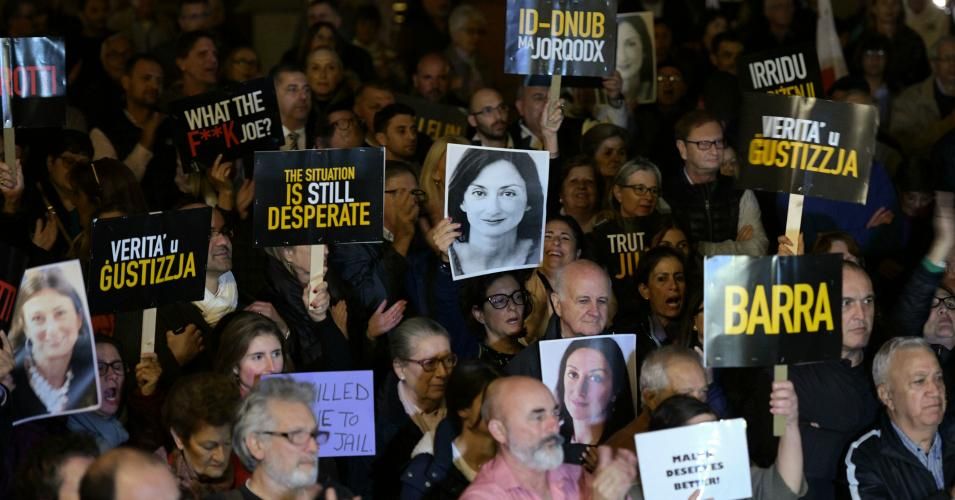 Protesters hold up placards and pictures of the late journalist Daphne Caruana Galizia 