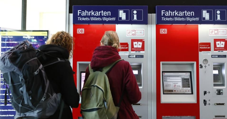 Passengers stand in front of the Deutsche Bahn ticket counter 