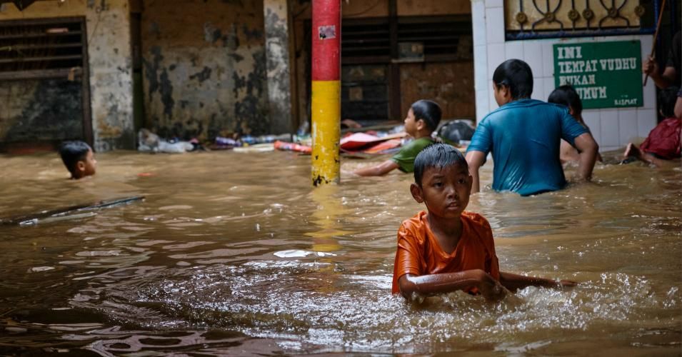 Indonesian children wade in their flooded neighborhood