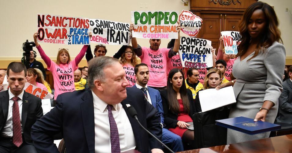 Protesters hold up signs before Secretary of State Mike Pompeo testifies before the House Foreign Affairs Committee on February 28, 2020. 