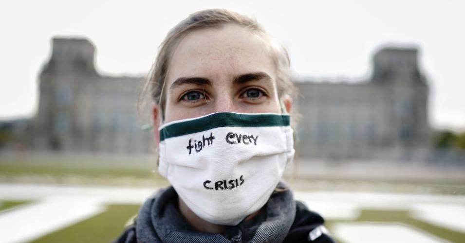  An activist from Fridays for Future in a face mask with the inscription "Fight every crisis" takes part in the alternative climate strike on the Reichstag meadow in Berlin. 