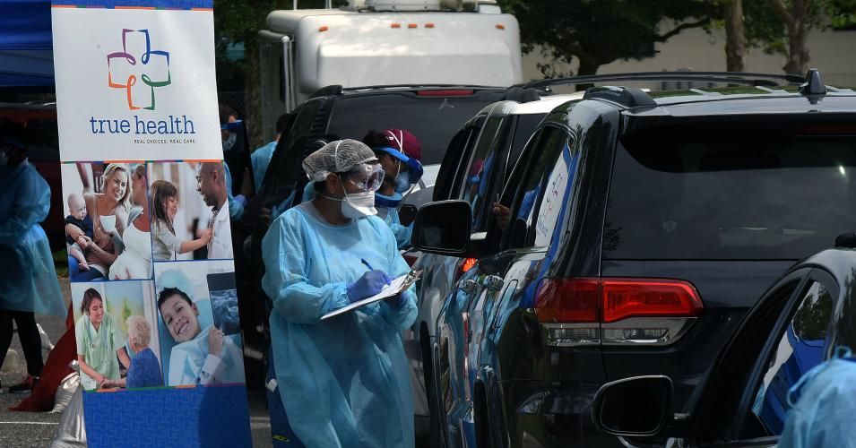 Health workers greet people as they arrive in cars at a mobile Covid-19 testing site at the Westside Community Center in the Goldsboro neighborhood of Sanford, Florida on April 23, 2020. 
