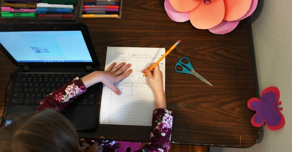 Eight-year-old Indi Pineau, a 3rd grader in Jeffco Public Schools, works on doing her first day of online learning in her room at her family's home on March 17, 2020 in Lakewood, Colorado. 
