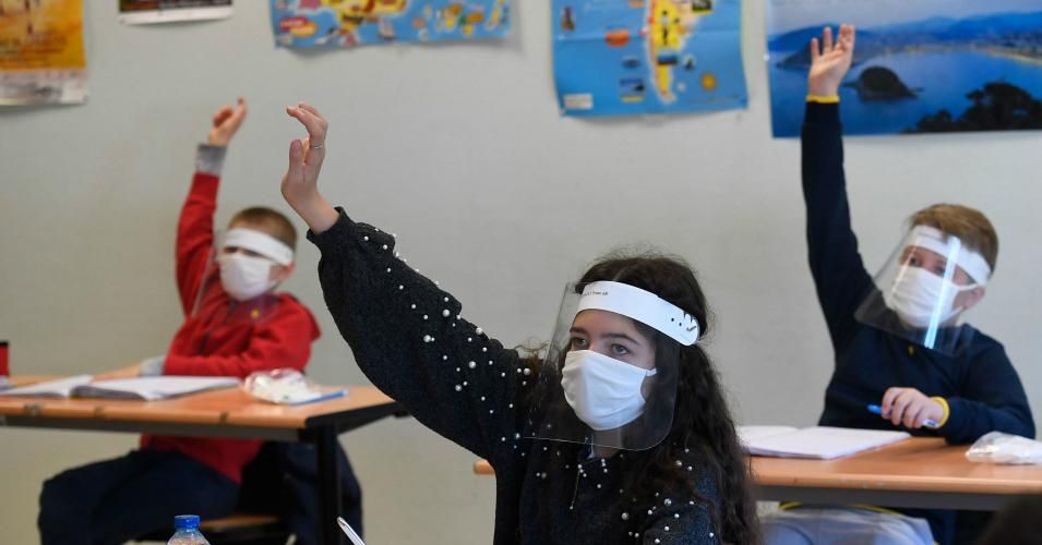 Schoolchildren wearing protective mouth masks and face shields attend a course in a classroom at Claude Debussy college in Angers, western France, on May 18, 2020 after the country eased Covid-19 lockdown measures. 